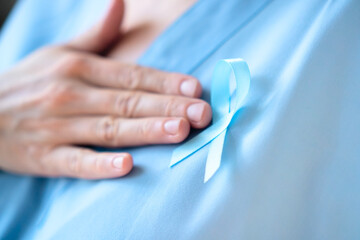 Close up of woman doctor in uniform with blue ribbon on clothes. Prostate cancer awareness month in November, prevention, early diagnosis, and oncology care reminder concept.