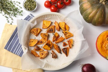 Baked pumpkin and ingredients on white table, flat lay