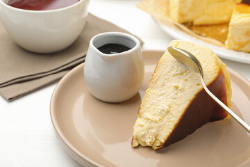 Piece of delicious Basque cheesecake, chocolate sauce and tea on white wooden table, closeup