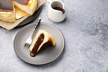 Delicious Basque cheesecake with chocolate sauce and fork on grey table, above view. Space for text