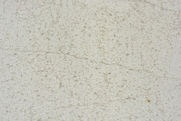 Construction and renovation work, plastering load-bearing street walls in sunlight. The white walls are coated with rough street primer with long micro-cracks throughout the surface and background.