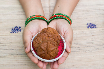 Lady hand with bangle holding wooden basket with thekua prasad. Famous festival chhath puja held in...