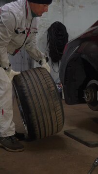 A mechanic installs a wheel on a car. Car repair at a service center.