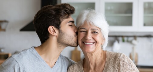 The older woman smiling as a young man kisses her cheek in kitchen