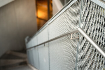 Close-up at metal railing banister handle with lower floor level as blurred background. Building...