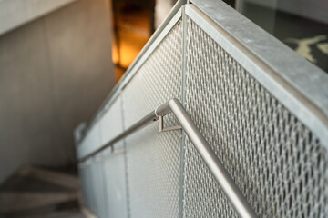 Close-up at metal railing banister handle with lower floor level as blurred background. Building...