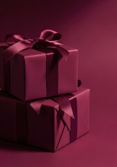 Two elegant, burgundy gift boxes adorned with ribbons against a deep mulberry plum background, festive and luxurious appearance.