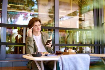 Young man enjoying a meal while working on his notebook in a modern cafe