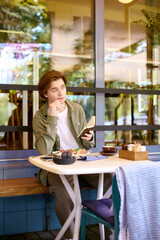 Young man enjoys reading and dining at modern cafe in the afternoon light