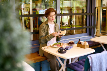 Young man enjoys a delicious meal while relaxing in a stylish cafe