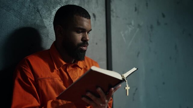 African American inmate reading Bible behind bars, spiritual repentance