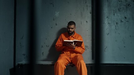 African American inmate reading Bible behind bars, seeking faith in confinement