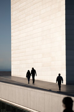 People walking up white architectural ramp under warm sunlight showing urban energy human rhythm and harmony between scale and minimal design in Oslo modern environment