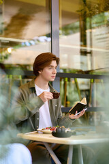 Young man enjoys meal while reading in a modern cafe with a relaxed atmosphere