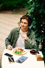 Young man enjoys a delicious meal in a modern cafe surrounded by greenery