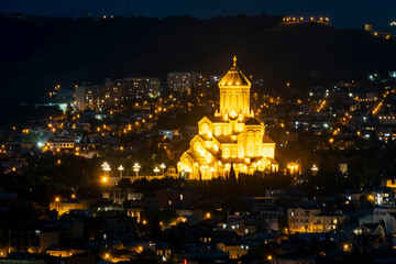 Stunning illuminated church towering over the city at night in Tbilisi, Georgia with glowing lights illuminating the skyline