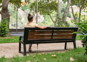 Relaxing on a park bench in a green space surrounded by trees on a sunny day