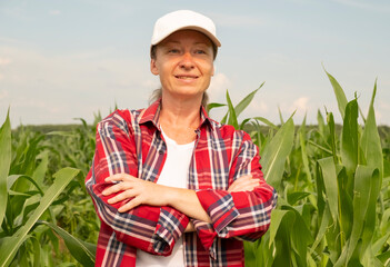 Woman in plaid shirt stands confidently in a cornfield during a sunny day in rural farmland