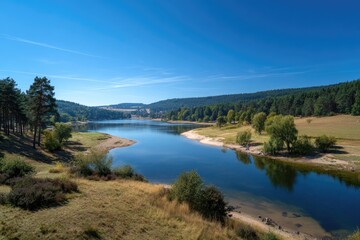 Fototapeta premium Serene lake surrounded by forest under a clear blue sky