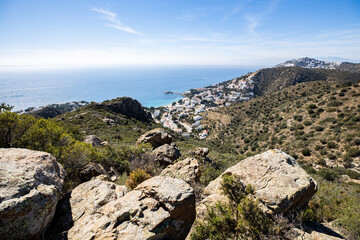 Stunning coastal view of Roses Spain with turquoise water, rocky cliffs, and charming white houses cascading down the hillside under a sunny sky