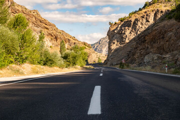 Fototapeta premium Scenic mountain road with clear skies and rocky landscape in the afternoon light
