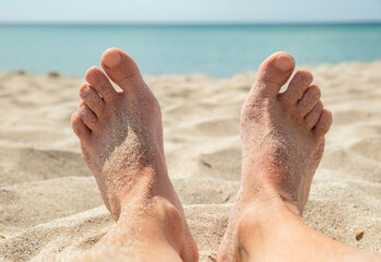 Relaxing on a sunny beach with bare feet in the warm sand and gentle waves in the background