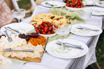 Summer outdoor picnic table with wildflowers, fruits, and elegant glassware.
