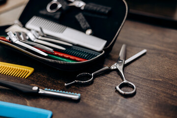 Hair scissors and colorful combs on wooden table in professional salon.