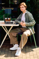Young man enjoys freelance work on his laptop at a modern cafe