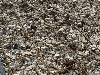Crushed stone with reinforcing mesh. Preparation for pouring the concrete base. Metal fittings texture