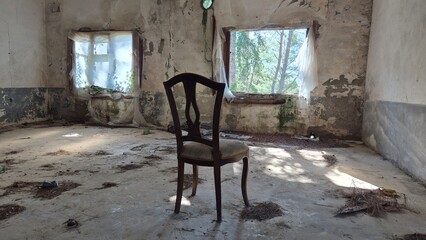 lonely wooden chair in abondoned, decaying room