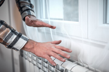 Obraz premium Man heating on a chilly winter day, energy and gas crisis, cold room, heating problems.