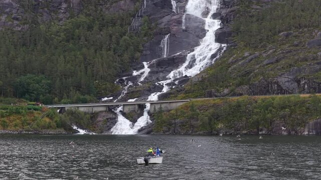Langfossen waterfall flows near fishing vessel in remote Norway view