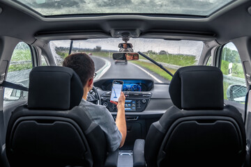 Driver using smartphone in rain. Navigation on the move.