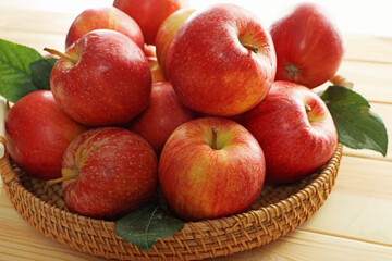 Fresh apples and green leaves on wooden table, closeup