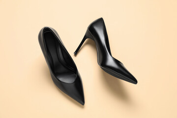 Pair of elegant black heels on beige background, top view. Stylish shoes