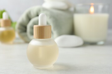 Essential oils, towel, spa stones and burning candle on white table, closeup. Space for text