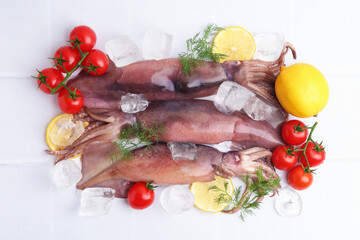 Raw squids, ice cubes, tomatoes, lemon slices and dill on white tiled table, flat lay