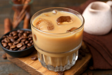 Tasty iced coffee with milk and beans on wooden table, closeup