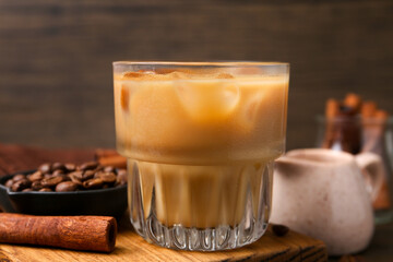 Tasty iced coffee with milk, cinnamon and beans on wooden table, closeup