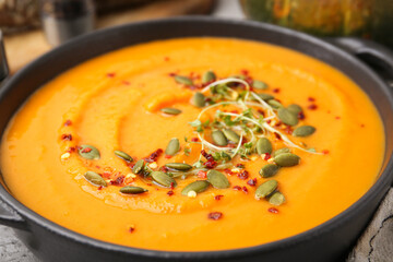 Delicious pumpkin soup in bowl on table, closeup