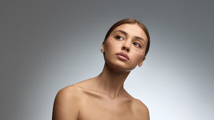 Portrait of woman with surgical markings and serious expression before aesthetic procedure. Concept of medical precision, facial anatomy, surgery planning, and patient awareness.