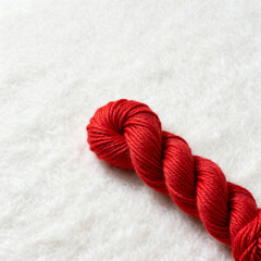 Red yarn on white textured surface