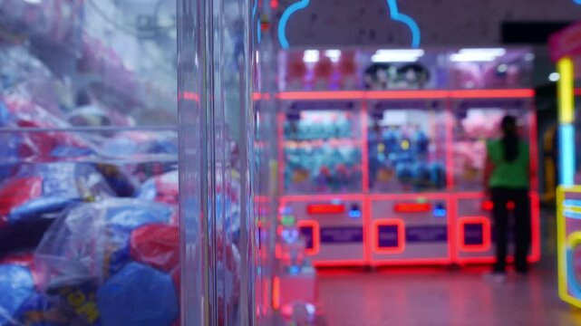 Vibrant Arcade Claw Machine Games with Glowing LED Lights in Indoor Amusement Venue