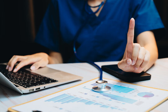 Healthcare analytics concept. Medical professional analyzing patient data and statistics while using a laptop and holding a stethoscope in an office setting