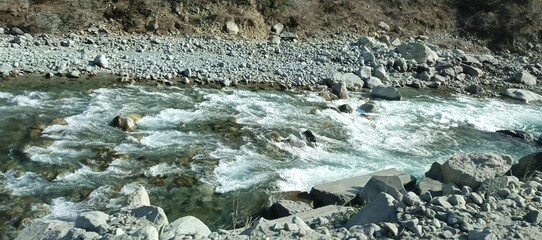 Close-up of Rapid Turquoise River Water Flowing Over Grey Boulders and Rocks