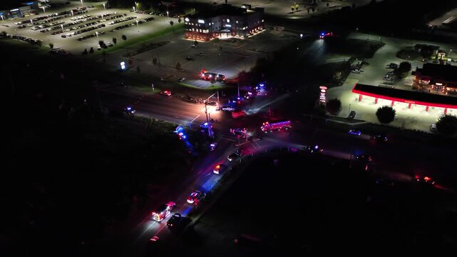 Aerial approaching shot of car accident on suburb junction road at night. Fire Truck, Police Car and Ambulance on street. American suburb district in Pennsylvania, USA.