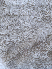 White faux fur texture close-up. High-resolution photo of soft, curly, and fluffy synthetic fur in light neutral tones. Ideal for cozy backgrounds, textile references, or winter-themed design.