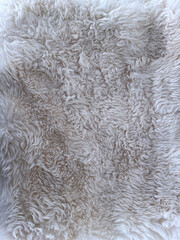 White faux fur texture close-up. High-resolution photo of soft, curly, and fluffy synthetic fur in light neutral tones. Ideal for cozy backgrounds, textile references, or winter-themed design.