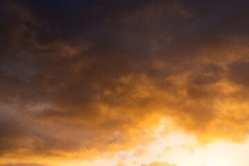Warm golden light illuminating dramatic clouds at sunrise creating a moody and atmospheric sky